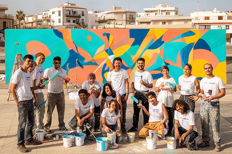 Grupo de jóvenes de una cooperativa trabaja frente a un mural recién pintado